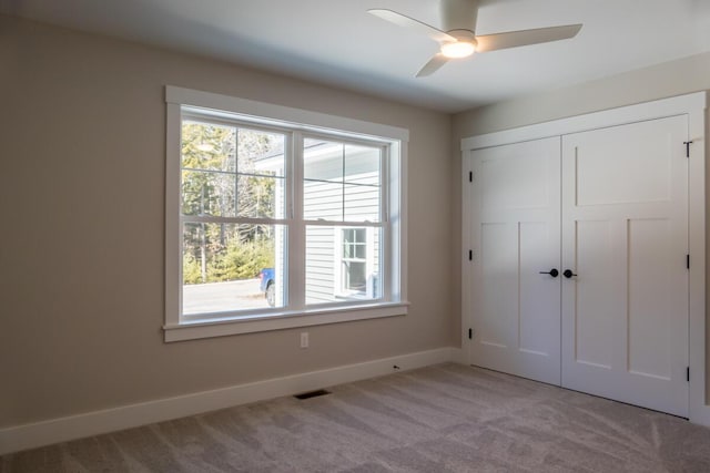 unfurnished bedroom featuring visible vents, a closet, carpet, baseboards, and ceiling fan