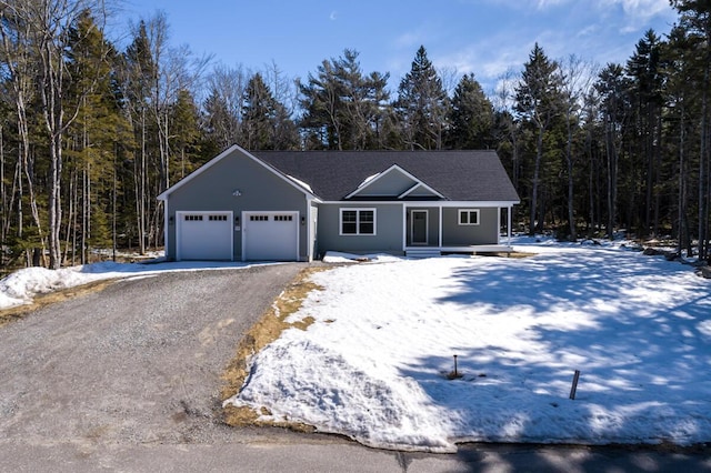 view of front of property with a garage, a view of trees, and driveway