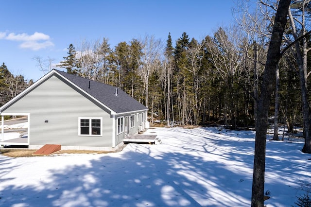 snow covered property with a shingled roof