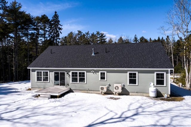 snow covered back of property featuring a wooden deck and roof with shingles