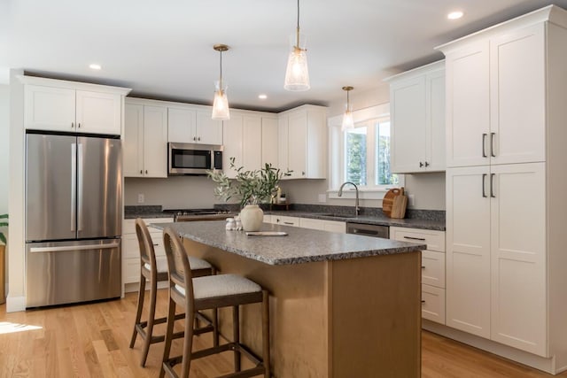 kitchen featuring white cabinetry, light wood-style flooring, appliances with stainless steel finishes, and a center island