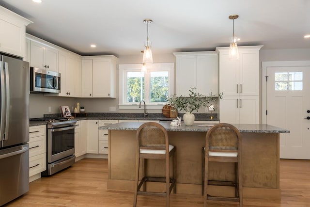 kitchen featuring a kitchen island, recessed lighting, stainless steel appliances, a kitchen bar, and light wood-type flooring