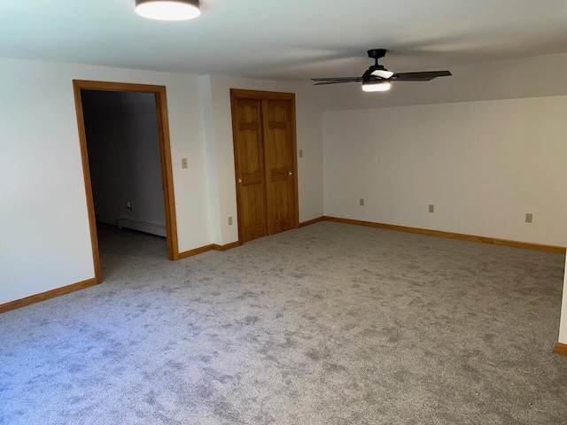 empty room with a baseboard heating unit, carpet flooring, baseboards, and ceiling fan