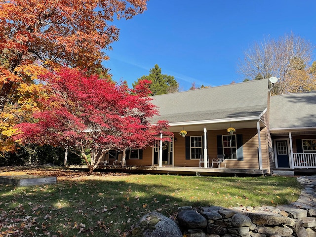 rear view of property featuring covered porch and a lawn