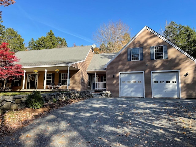 view of front of house featuring driveway, covered porch, and a garage