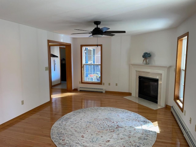 living area with baseboard heating, baseboards, a ceiling fan, and wood finished floors