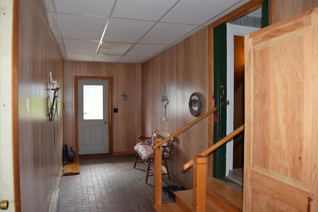 foyer entrance with a paneled ceiling and wood walls