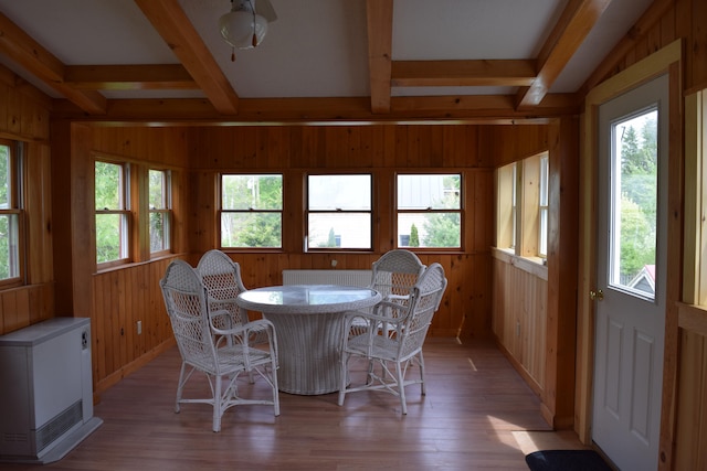 dining space with a wealth of natural light, wooden walls, and hardwood / wood-style flooring