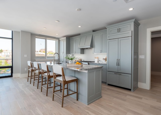 387 Commercial St Unit 709, Portland, ME 04101 - kitchen with gray cabinetry, custom range hood, a sink, light wood finished floors, and recessed lighting
