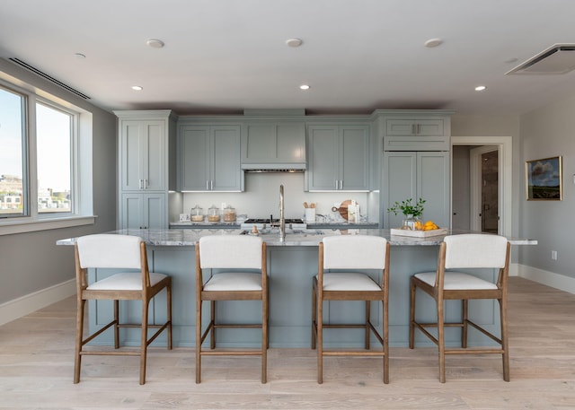 387 Commercial St Unit 709, Portland, ME 04101 - kitchen featuring baseboards, a kitchen island with sink, light stone countertops, light wood-style flooring, and recessed lighting