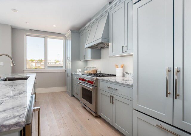 387 Commercial St Unit 709, Portland, ME 04101 - kitchen featuring designer range, a sink, custom range hood, gray cabinets, and baseboards
