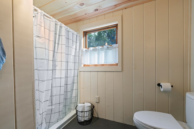 bathroom with tile patterned flooring, wood walls, toilet, and a shower with curtain