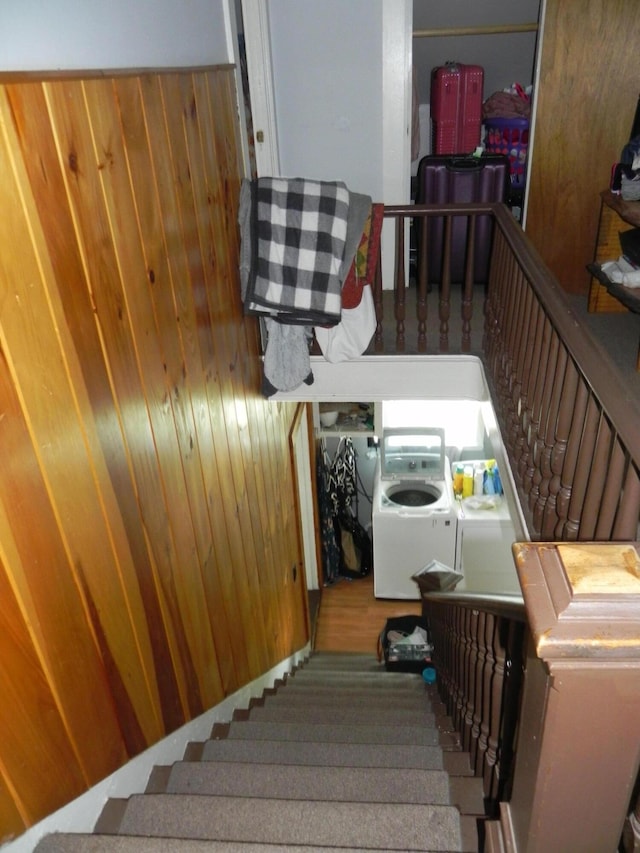 stairs with wood walls and independent washer and dryer