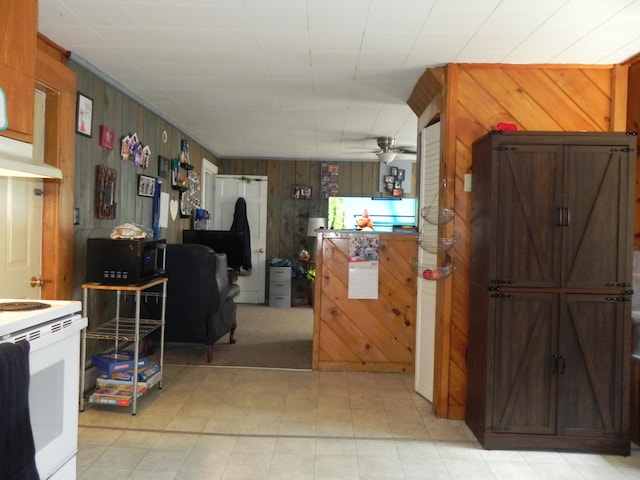 kitchen with ceiling fan, white electric range, and wooden walls