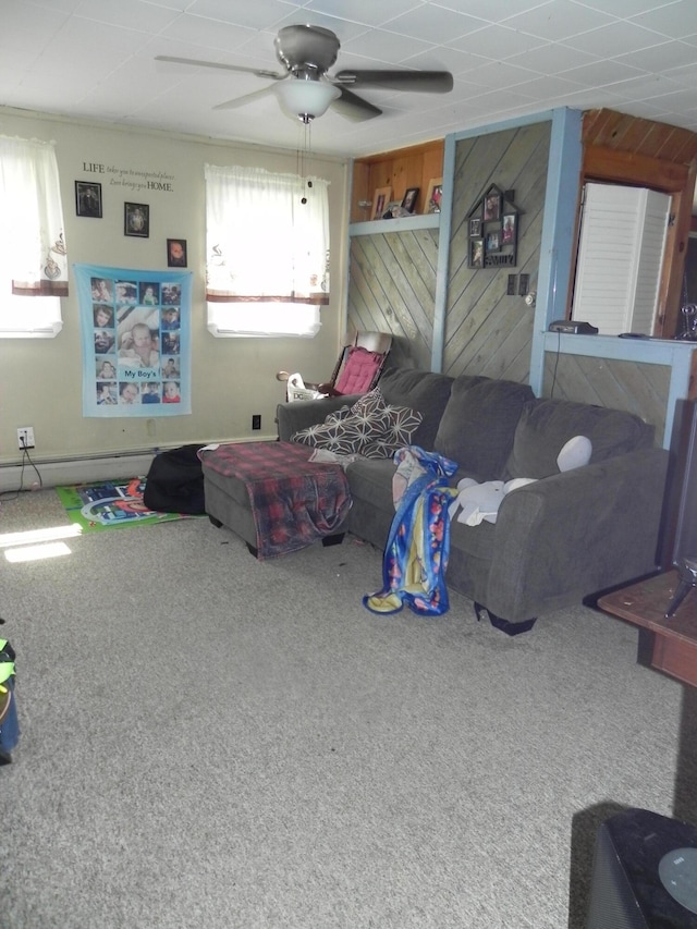 bedroom with ceiling fan, multiple windows, carpet floors, and wood walls