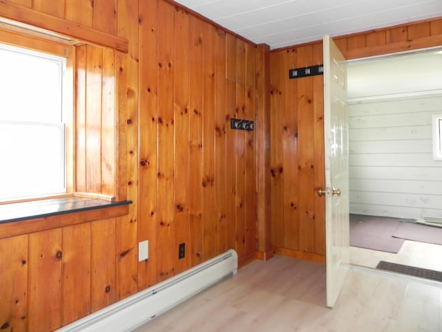 interior space with wooden walls, wood finished floors, and a baseboard radiator