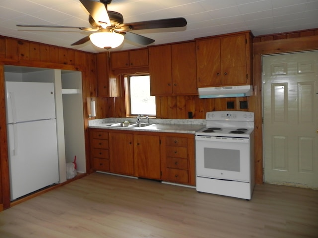 kitchen featuring a sink, brown cabinets, white appliances, light wood-type flooring, and under cabinet range hood