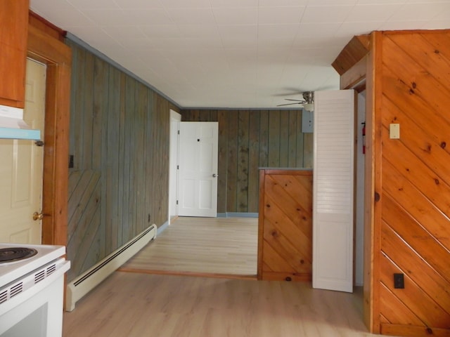 hallway with baseboard heating, wood walls, and light wood-style floors