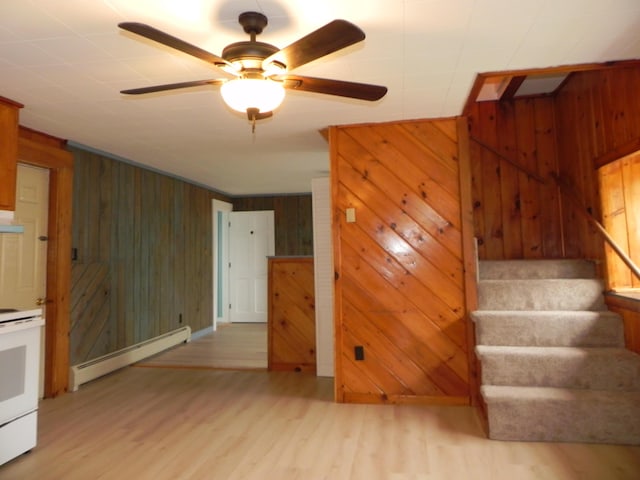 interior space featuring wood finished floors, baseboard heating, wooden walls, and a ceiling fan