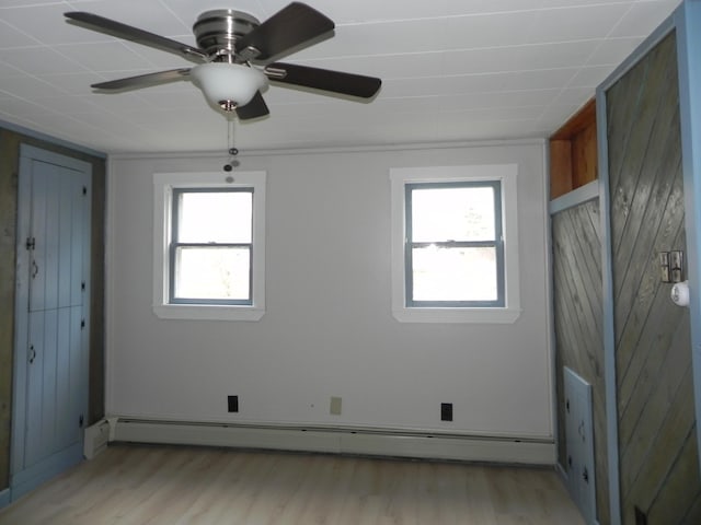 spare room featuring light wood finished floors, baseboard heating, and a ceiling fan