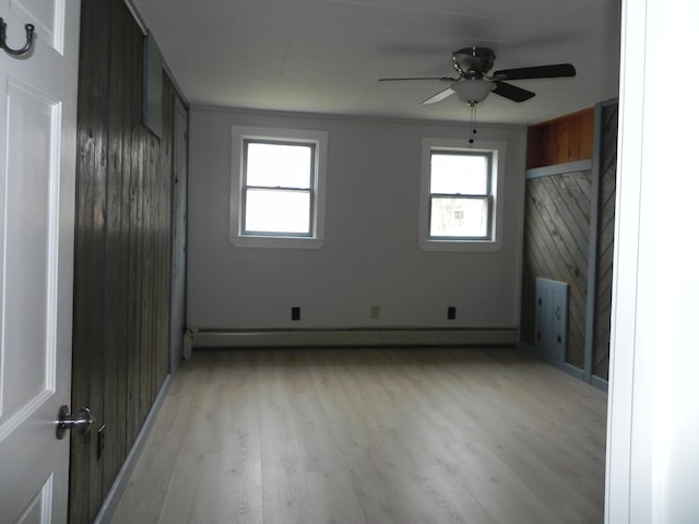 unfurnished living room featuring a baseboard radiator, a wealth of natural light, light wood finished floors, and a ceiling fan