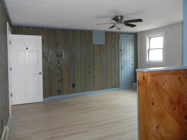 spare room with wooden walls, baseboards, light wood-style floors, and ceiling fan