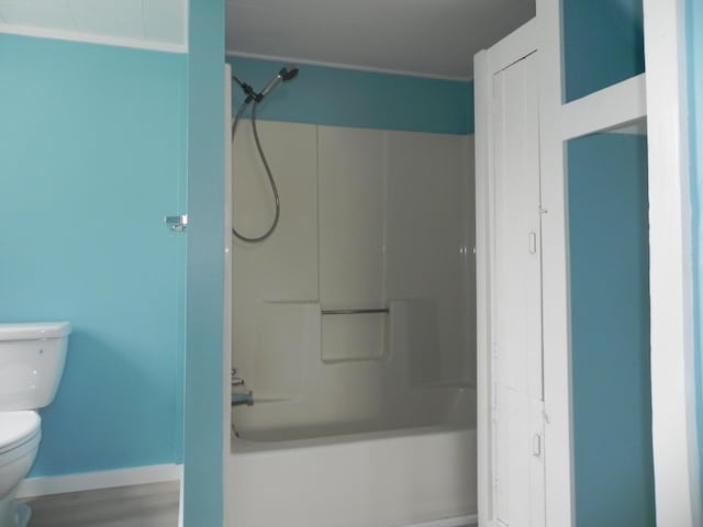 bathroom with toilet, baseboards, and bathtub / shower combination