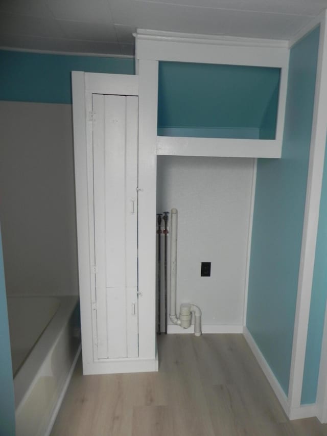 clothes washing area featuring wood finished floors and baseboards