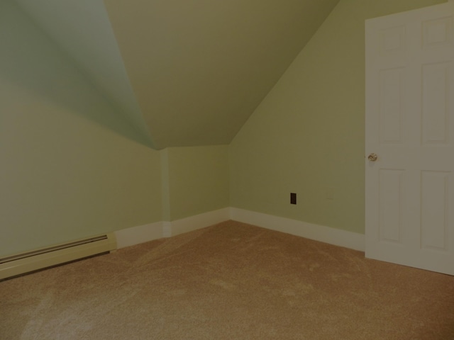 additional living space featuring a baseboard heating unit, light carpet, vaulted ceiling, and baseboards