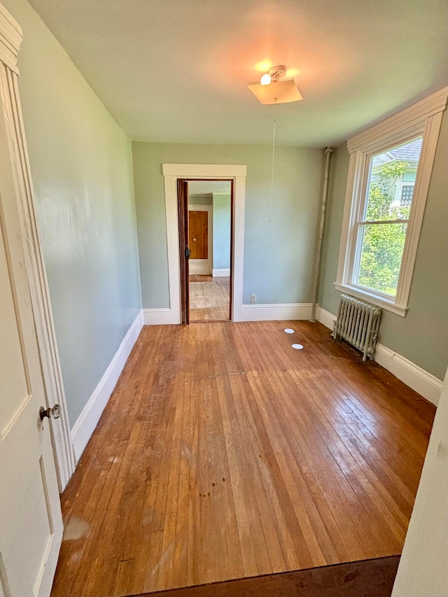 unfurnished room featuring radiator and wood-type flooring