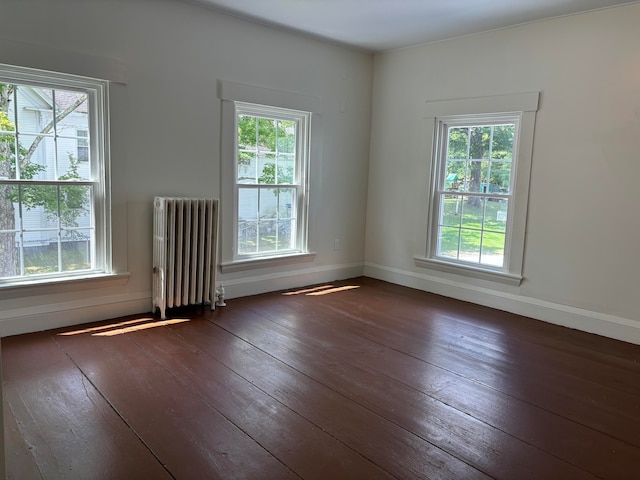 empty room with hardwood / wood-style floors, radiator, and plenty of natural light