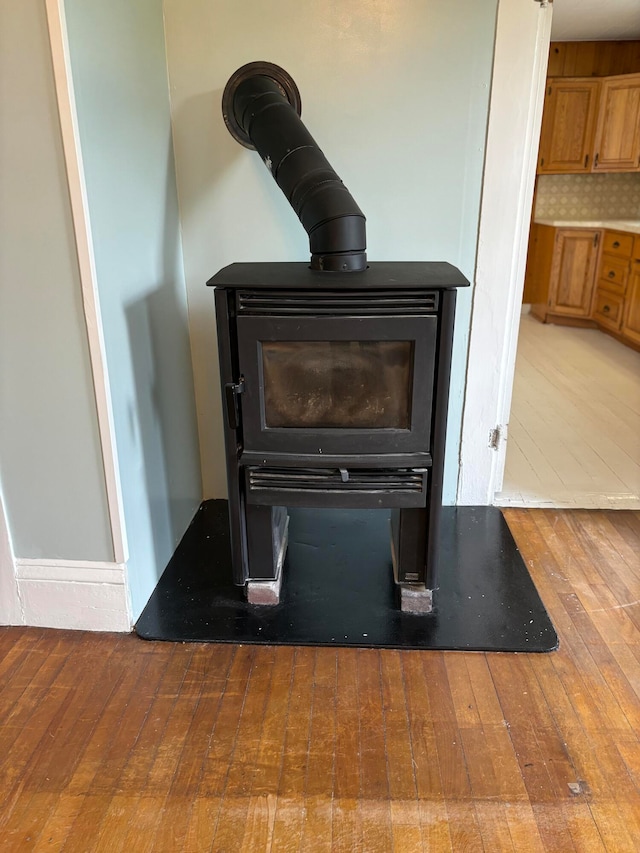 interior details featuring hardwood / wood-style floors, backsplash, and a wood stove