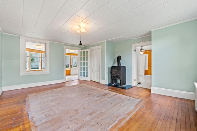 unfurnished living room with a wood stove, crown molding, and hardwood / wood-style flooring