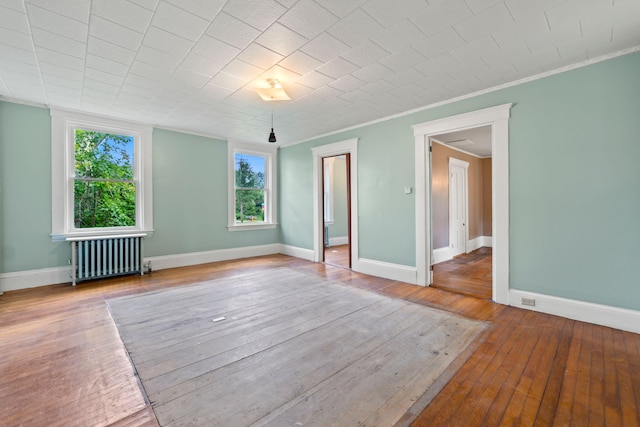 spare room with radiator heating unit, ornamental molding, and hardwood / wood-style floors