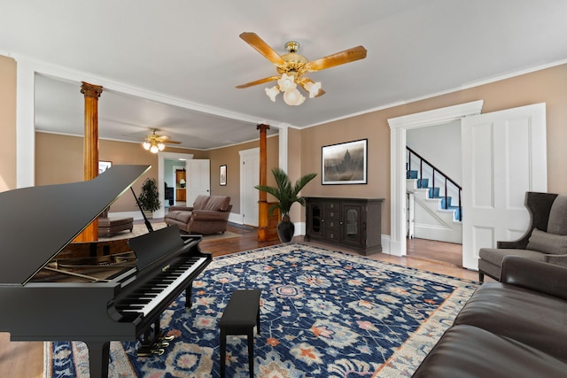 miscellaneous room with ceiling fan, decorative columns, light wood-type flooring, and ornamental molding