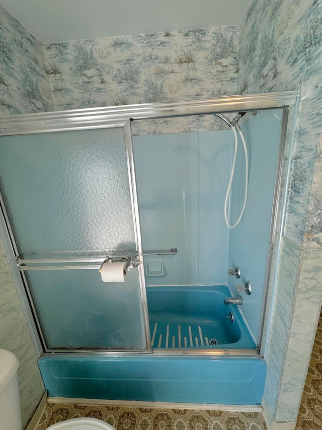 bathroom featuring shower / bath combination with glass door, tile patterned floors, and toilet