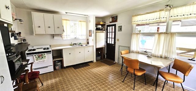 kitchen featuring white stove, white cabinetry, and sink