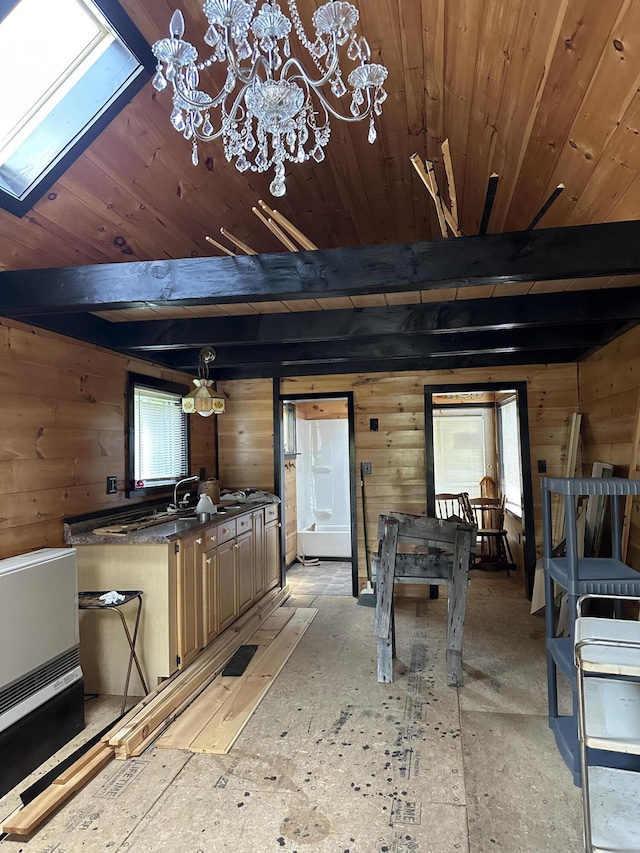 kitchen with beam ceiling, a skylight, and wood walls