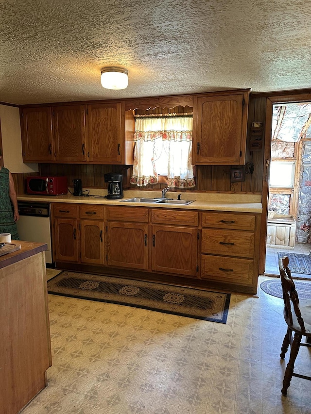 kitchen featuring a textured ceiling, dishwasher, and sink