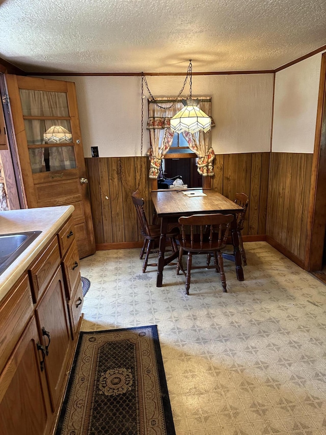 dining room with a textured ceiling, crown molding, and wooden walls