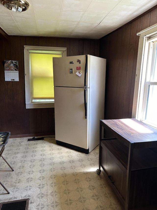 kitchen featuring white fridge and wooden walls