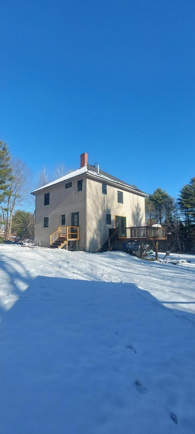 snow covered rear of property featuring a wooden deck