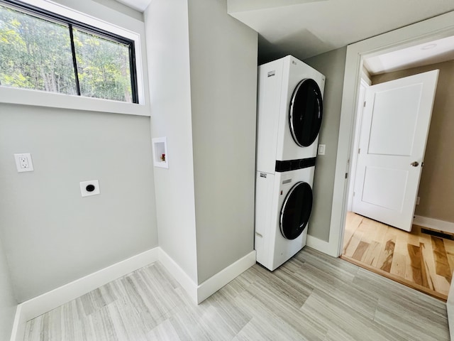 laundry room with stacked washer and clothes dryer and light hardwood / wood-style floors