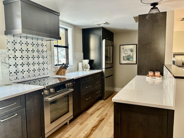 kitchen with light hardwood / wood-style flooring, backsplash, stainless steel appliances, ventilation hood, and light stone countertops