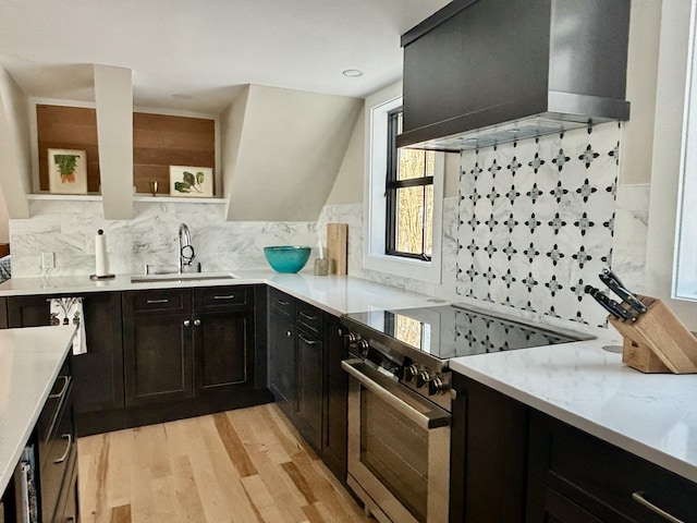 kitchen featuring sink, light stone counters, light hardwood / wood-style flooring, electric range, and wall chimney range hood