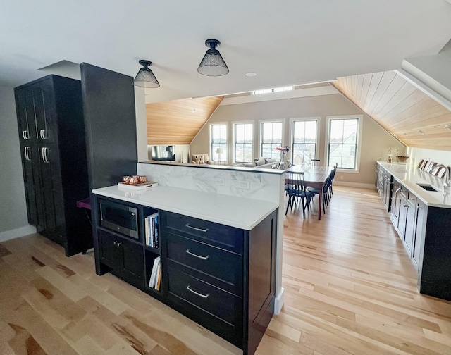 kitchen with vaulted ceiling, sink, a center island, wooden ceiling, and light hardwood / wood-style flooring