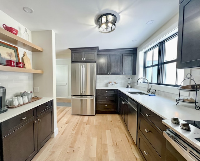 kitchen featuring tasteful backsplash, appliances with stainless steel finishes, sink, and light hardwood / wood-style floors