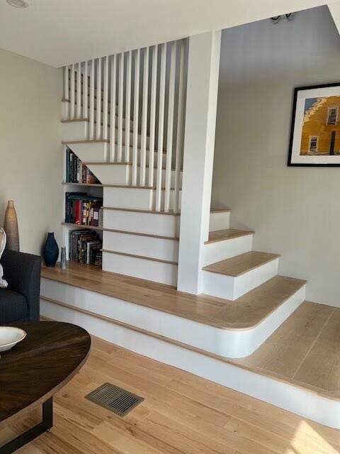 stairs with wood finished floors and visible vents