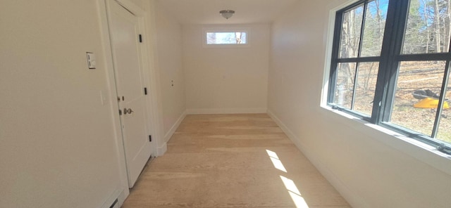 corridor featuring light wood-type flooring and baseboards