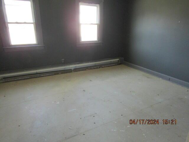 unfurnished room with a baseboard heating unit